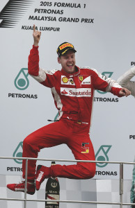 Ferrari driver Sebastian Vettel of Germany jumps on the podium as he celebrates after winning the Malaysian Formula One Grand Prix at Sepang International Circuit in Sepang, Malaysia, Sunday, March 29, 2015. (AP Photo/Andy Wong)