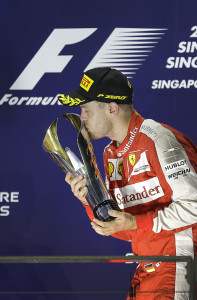 Ferrari driver Sebastian Vettel of Germany kisses the trophy on the podium after winning the Singapore Formula One Grand Prix on the Marina Bay City Circuit in Singapore, Sunday, Sept. 20, 2015. (AP Photo/Wong Maye-E)