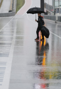 A Force India crew member walks across pit road as rain falls before the scheduled start of the third practice session for the Formula One U.S. Grand Prix auto race at the Circuit of the Americas, Saturday, Oct. 24, 2015, in Austin, Texas. (AP Photo/John Locher)