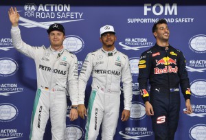 TOPSHOT - Mercedes AMG Petronas F1 Team's British driver Lewis Hamilton (C), flanked by his German teammate Nico Rosberg (L) and Infiniti Red Bull Racing's Australian driver Daniel Ricciardo, celebrate at the end of the qualifying session as part of the Abu Dhabi Formula One Grand Prix at the Yas Marina circuit on November 26, 2016. Lewis Hamilton will start on pole for the Abu Dhabi Grand Prix title showdown after the defending champion bettered his Mercedes teammate Nico Rosberg in qualifying. Red Bull's Daniel Ricciardo came in third to start on the second row at Yas Marina where the Australian is joined by the Ferrari of Kimi Raikkonen. / AFP PHOTO / Andrej ISAKOVIC