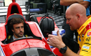Formula 1 driver Fernando Alonso, left, of Spain, talks with crew members as he is fitted for an IndyCar before the Indy Grand Prix of Alabama auto race Sunday, April 23, 2017, in Birmingham, Ala. (AP Photo/Butch Dill)