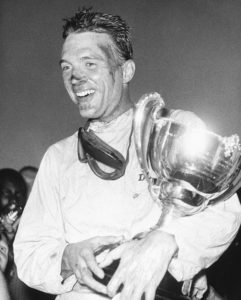 FILE - This Dec. 9, 1962 file photo shows Dan Gurney holding a trophy in Nassau, Bahamas. Gurney, the first driver to win in Formula One, IndyCar and NASCAR, died Sunday, Jan. 14, 2018 from complications of pneumonia. He was 86. His wife, Evi, announced his death in a statement distributed by All American Racers, Inc. (AP Photo)