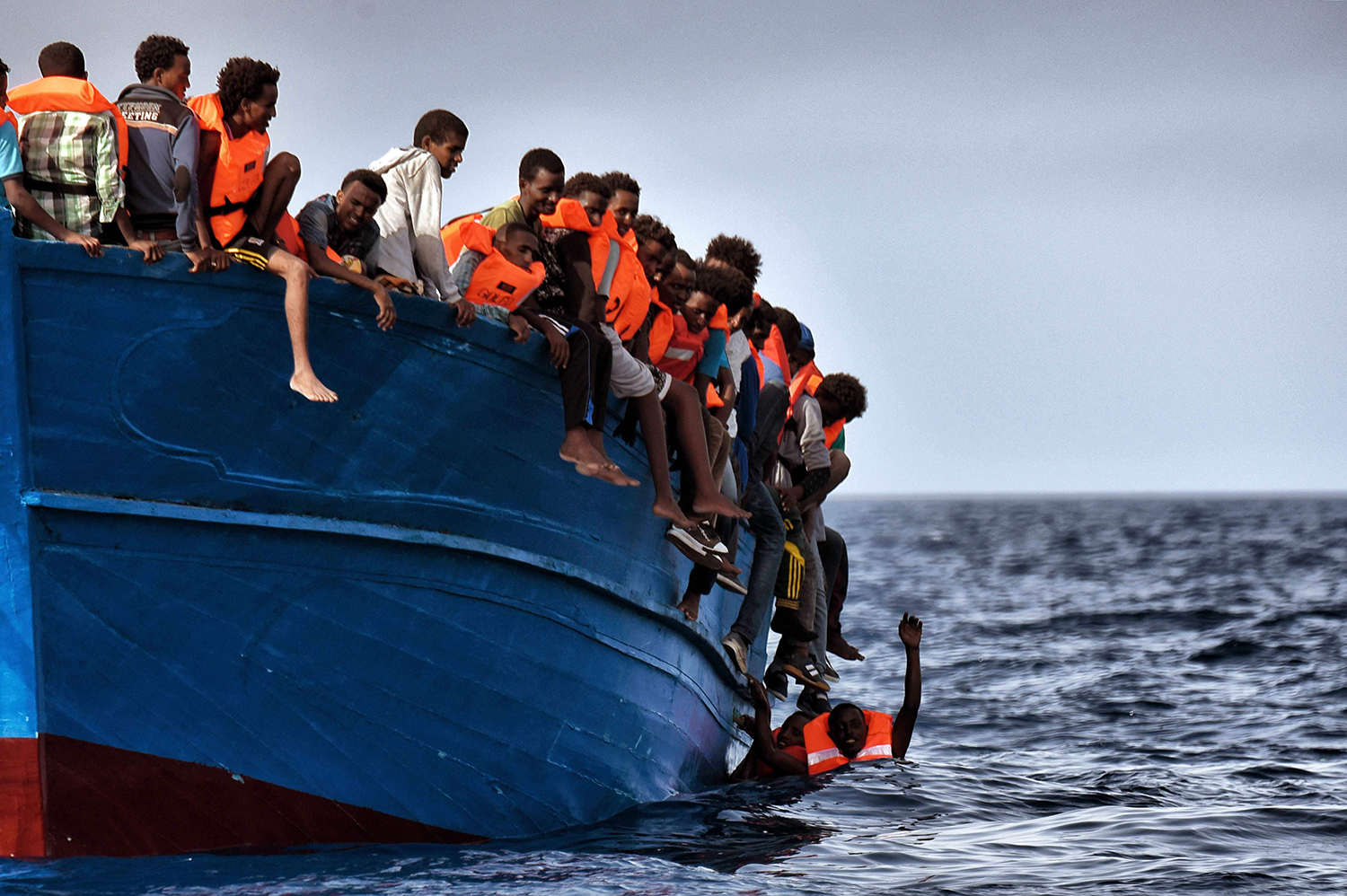 Migrants hang from a boat as they wait to be rescued as they drift in the Mediterranean Sea some 20 nautical miles north off the coast of Libya on October 3, 2016. / AFP PHOTO / ARIS MESSINIS / TT / kod 444