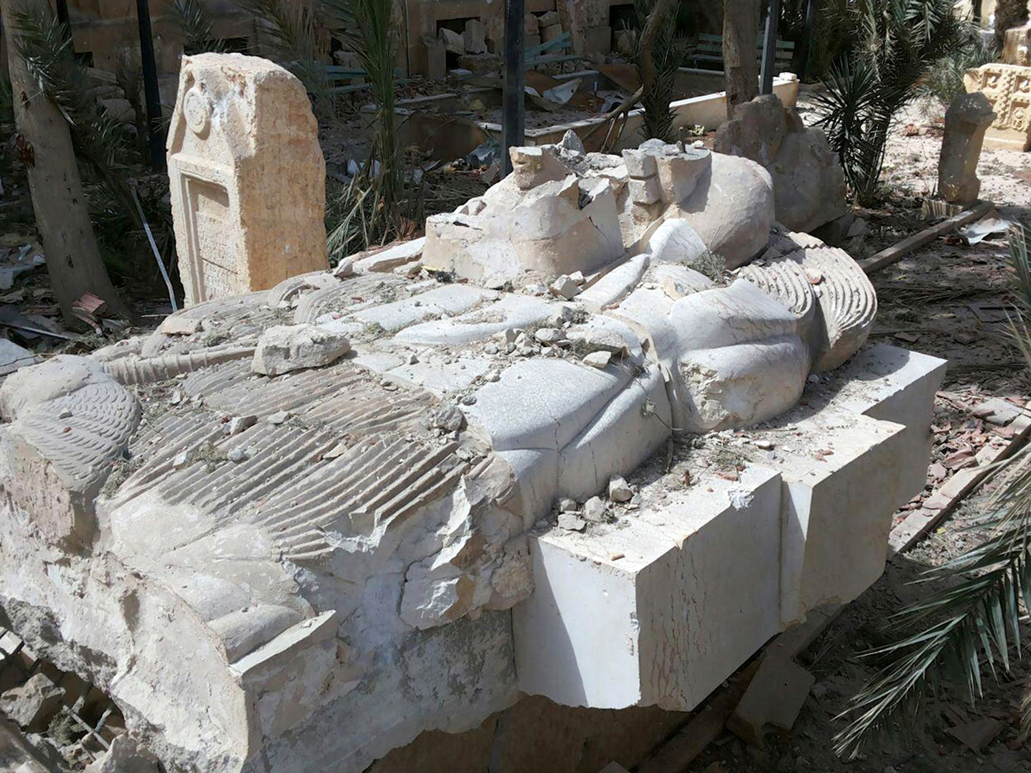 FILE - This file photo released March 27, 2016, by the Syrian official news agency SANA, shows a destroyed statue outside the damaged Palmyra Museum, in Palmyra city, central Syria. Palmyra, the archaeological gem that Islamic State fighters retook Sunday, Dec. 11, 2016, from Syrian troops, is a desert oasis surrounded by palm trees, and a UNESCO world heritage site, that boasts 2,000-year-old towering Roman-era colonnades and priceless artifacts. It is also a strategic crossroads linking the Syrian capital, Damascus, with the country's east and neighboring Iraq. (SANA via AP, File)