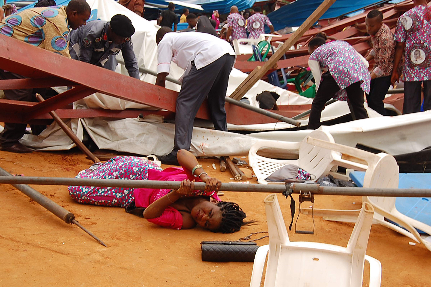 TOPSHOT - This picture taken on December 10, 2016 shows a woman stuck under a scaffolding bar amid rubbles at the scene after an evengelical church roof collapsed on worshippers in the remote southeastern city of Uyo, the capital of Akwa Ibom state. The search for survivors continued after a church roof collapsed killing at least 60 people, with many more feared dead. / AFP PHOTO / STRINGER / TT / kod 444