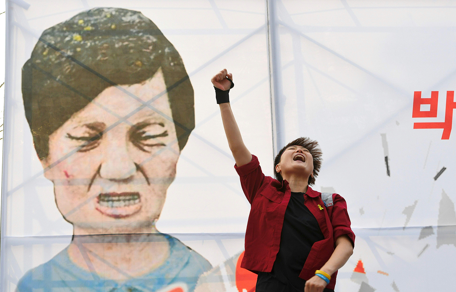 TOPSHOT - A protester shouts slogans in front of a caricature of South Korea's President Park Geun-Hye during a rally urging the impeachment of the president in Seoul on December 7, 2016. South Korea's scandal-hit Park said on December 6 she would accept the result of a looming and possibly lengthy impeachment process, but defied pressure to resign immediately. / AFP PHOTO / JUNG Yeon-Je / TT / kod 444