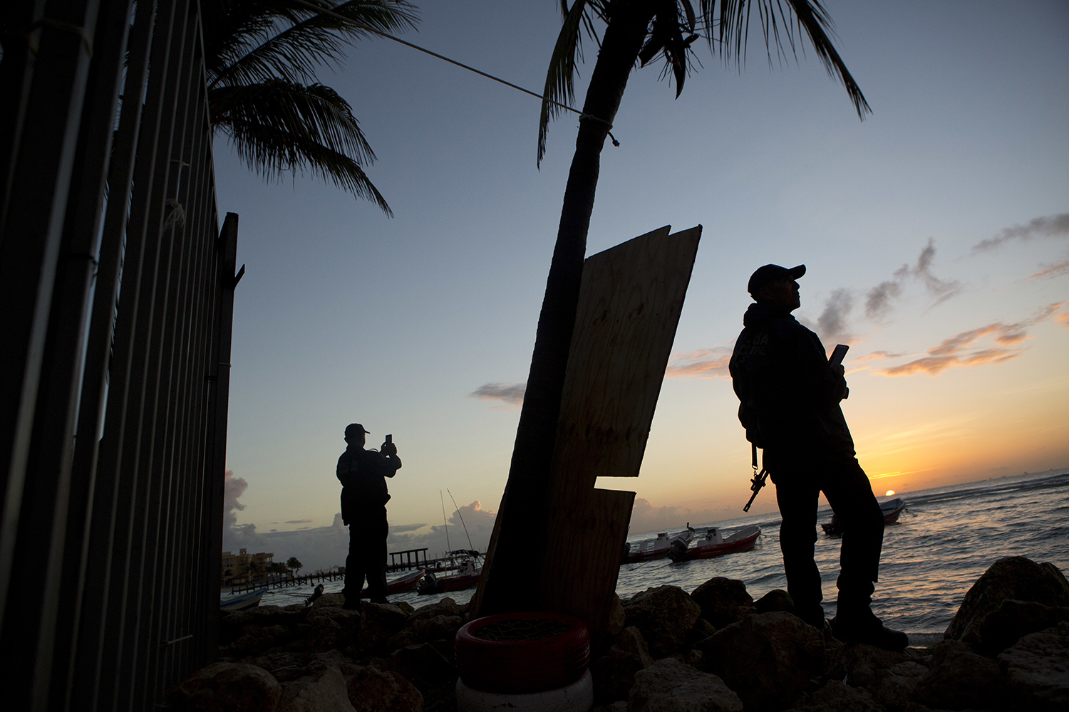 Municipal police watch the sunrise as they stand guard on the beach in front of the Blue Parrot club, a day after a deadly early morning shooting, in Playa del Carmen, Mexico, Tuesday, Jan. 17, 2017. Mexican authorities said Tuesday they are investigating whether extortion, street-level drug sales or a murder plot was the motive behind a shooting at an electronic music festival at a Caribbean resort town that left three foreigners and two Mexicans dead.(AP Photo/Rebecca Blackwell)