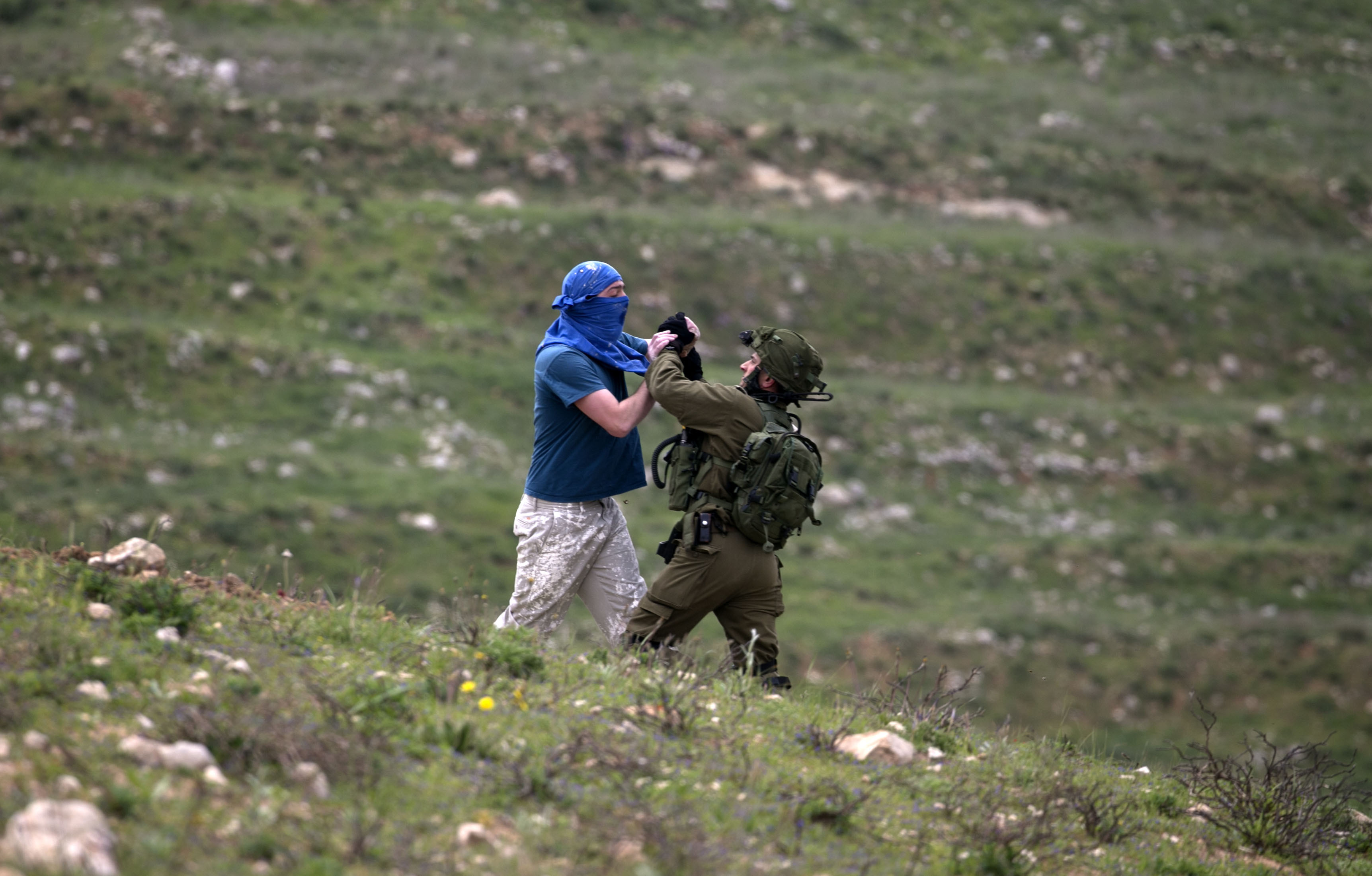 TOPSHOT - An Israeli soldier scuffles with a masked Israeli settler while trying to remove him from the area of a protest by Palestinians on March 30, 2017, to mark land day, in village of Madama south of Nablus in the Israeli occupied West Bank. Land Day marks the killing of six Arab Israelis during 1976 demonstrations against Israeli confiscations of Arab land. / AFP PHOTO / JAAFAR ASHTIYEH / TT / kod 444