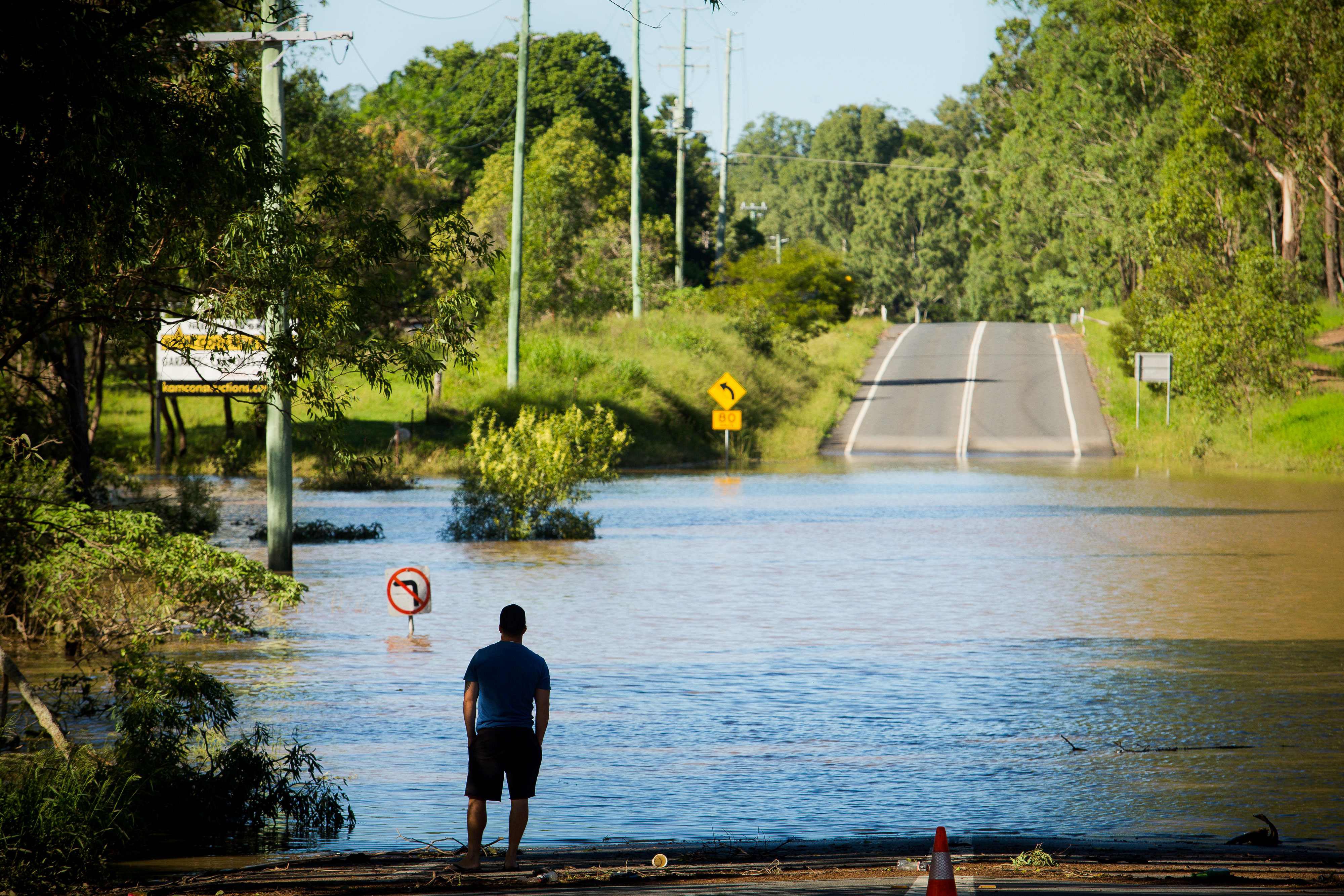 TOPSHOT - A resident looks at a road, submerged under floodwaters caused by Cyclone Debbie, in North MacLean, Brisbane on April 1, 2017. Flooded rivers were still rising on April 1 in two Australian states with two women dead and four people missing after torrential rains in the wake of a powerful tropical cyclone. / AFP PHOTO / Patrick HAMILTON / TT / kod 444