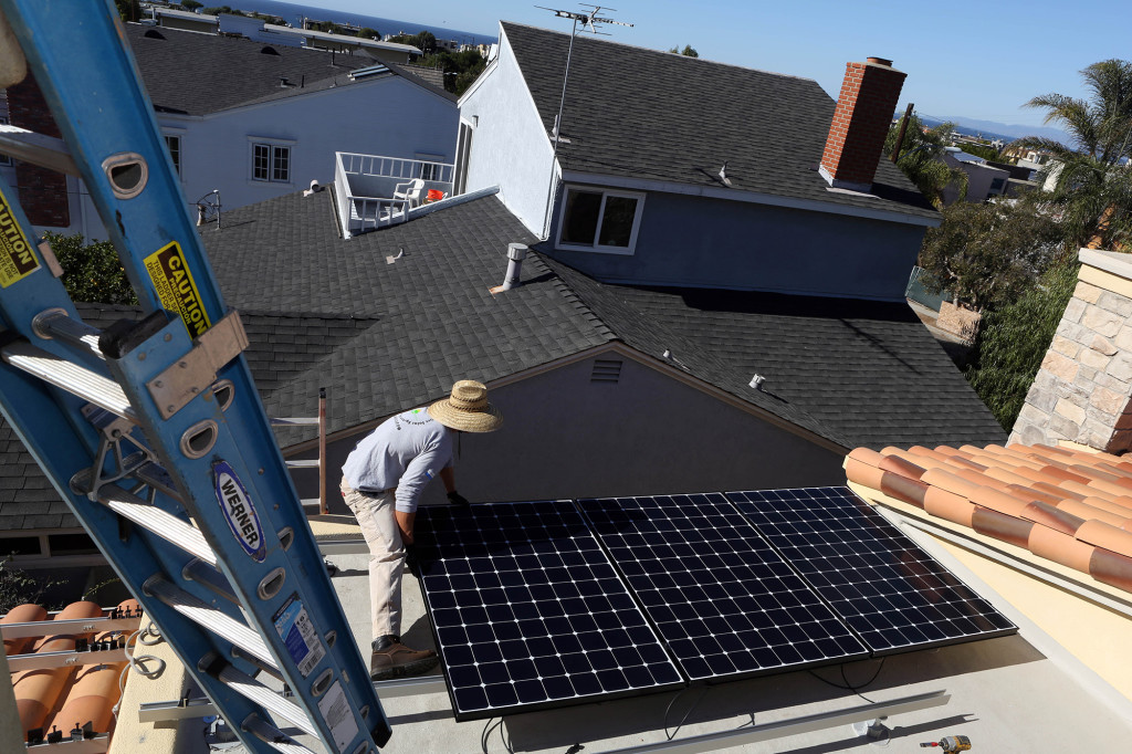 Kirk Mueller installerar solceller på ett hustak i Manhattan Beach.